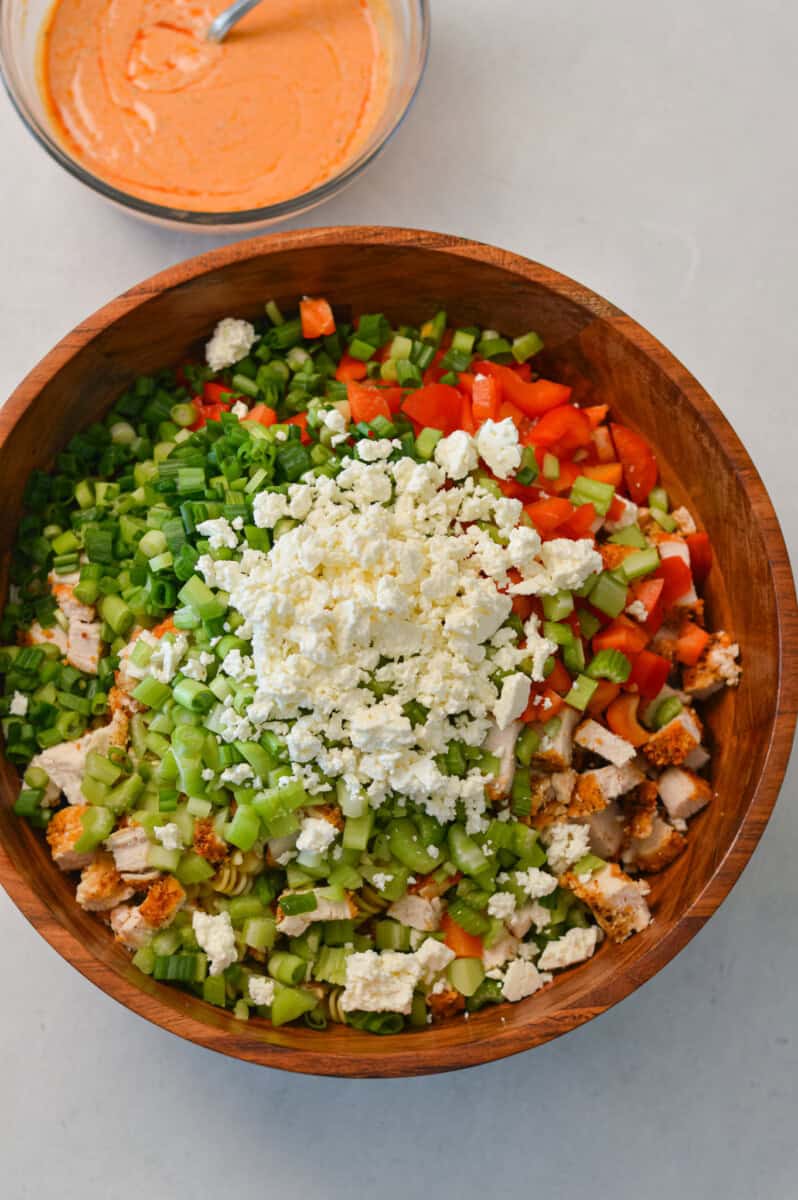 All ingredients for the buffalo chicken salad added to a large salad bowl.
