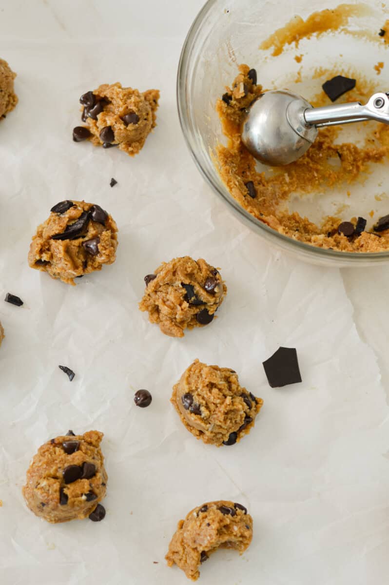 Cookie dough bites scooped onto parchment paper.
