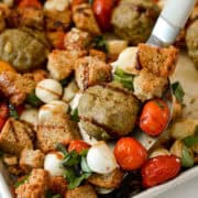 Close up of pesto chicken meatballs being lifted off the pan