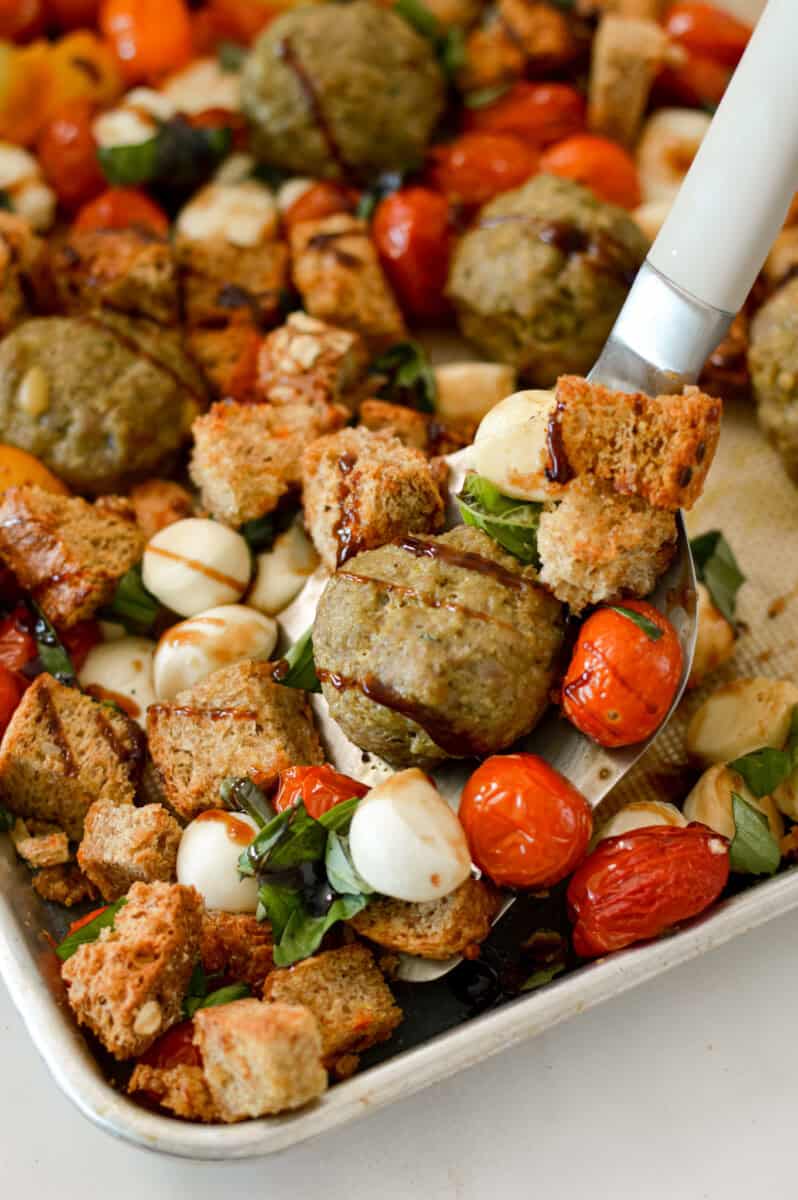Close up of pesto chicken meatballs being lifted off the pan