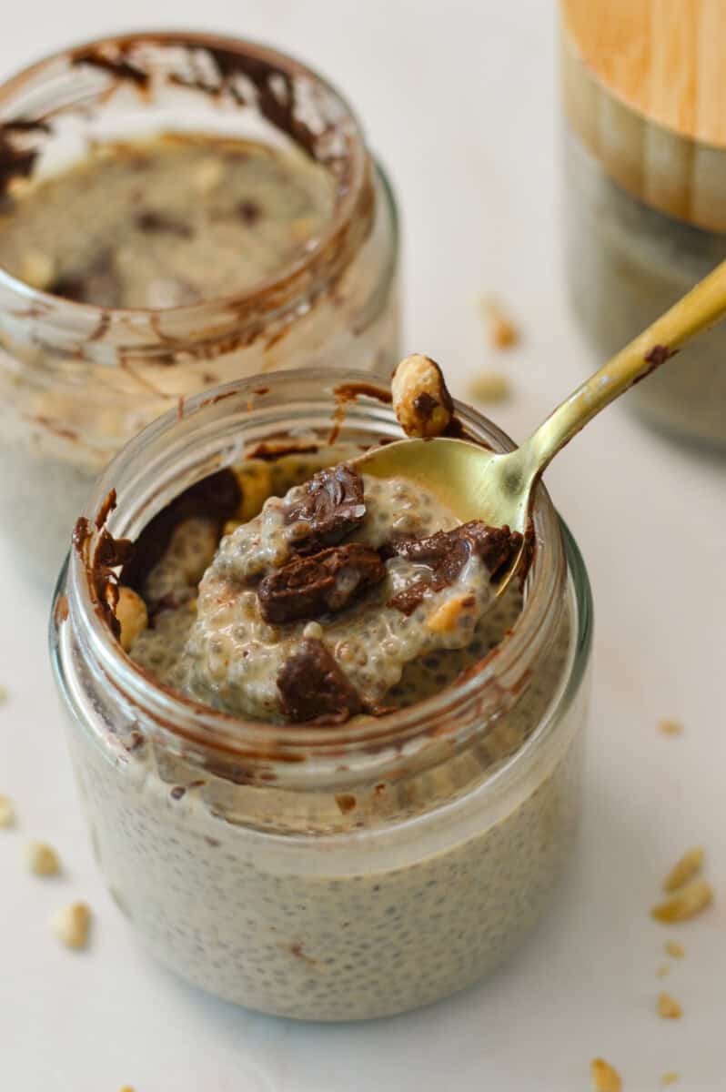 Spoon lifting up a bite of the chocolate peanut butter cup chia putting out of a jar.