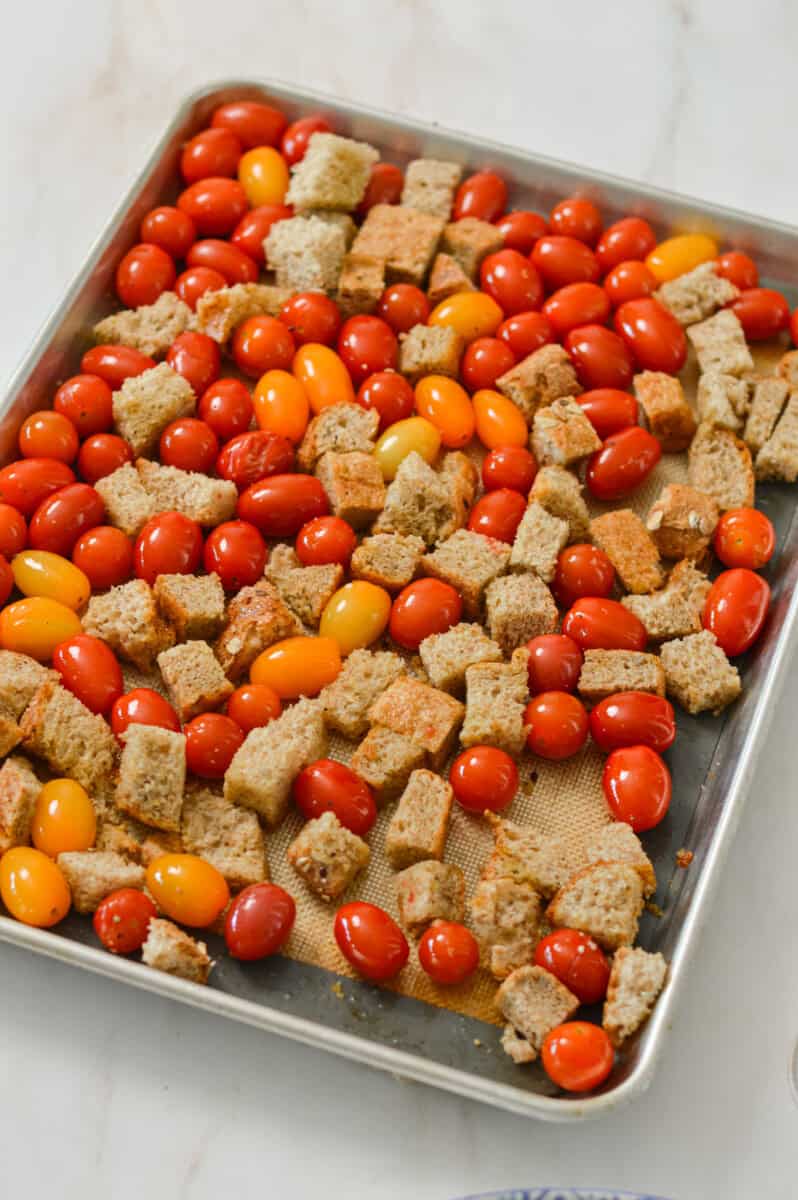 Cherry tomatoes and sourdough bread on a sheet pan.