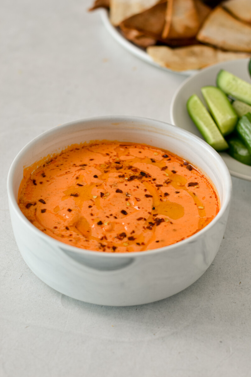Easy red pepper dip in a bowl topped with olive oil and chili flakes.