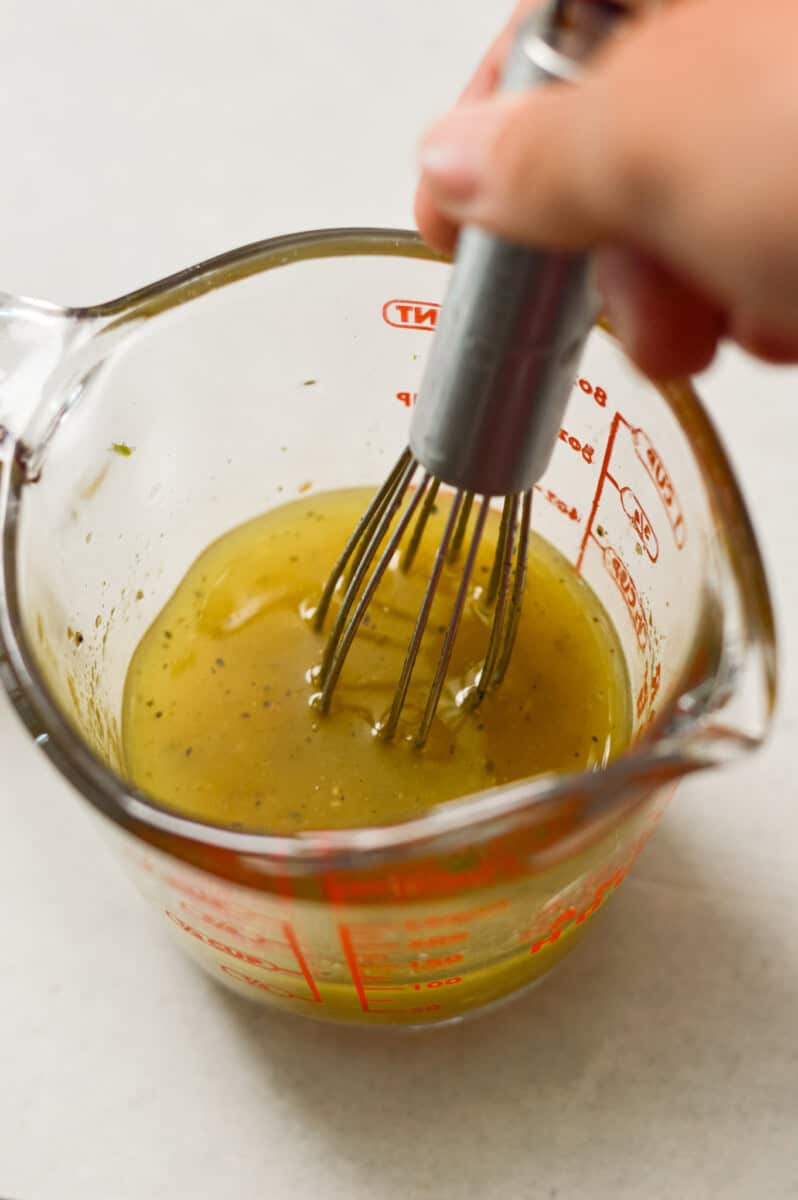 Dressing being whisked in a measuring cup.