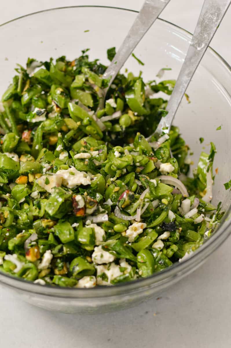 Snap pea salad tossed in a glass bowl.