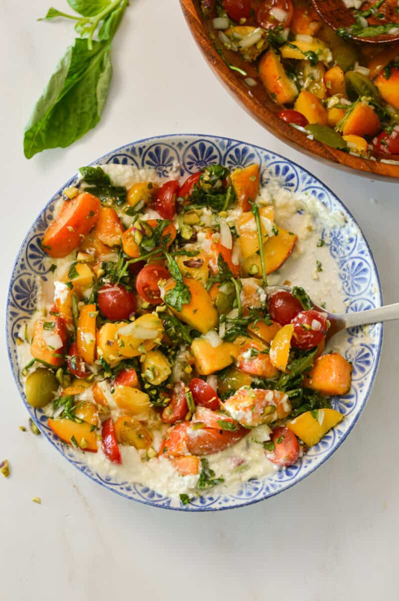 Birdseye of tomato, peach and burrata salad in a bowl.