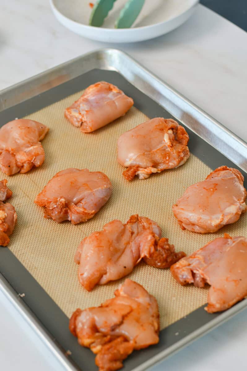 Chicken thighs with spices on a sheet pan.