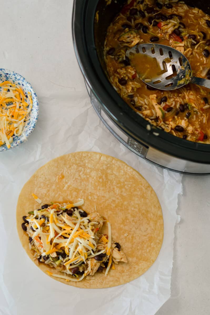 Green chili chicken added to a wrap and topped with cheese.
