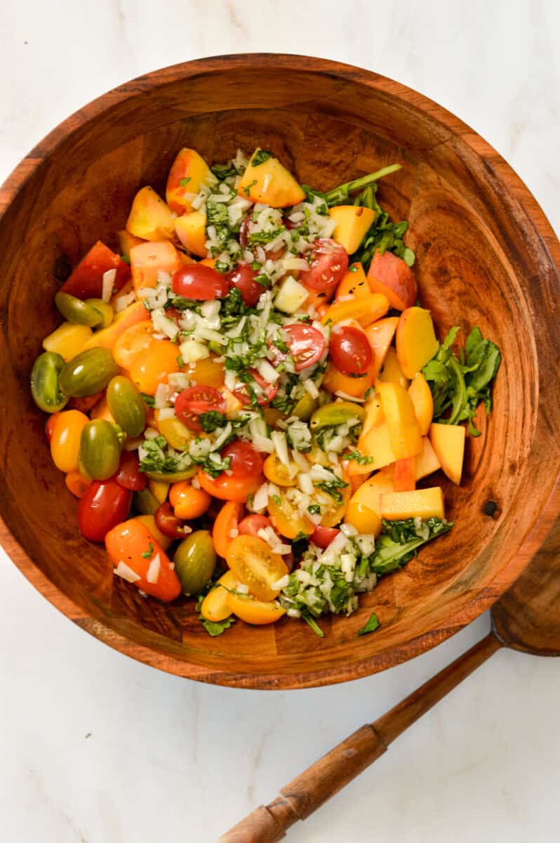 Peaches and tomatoes added to a salad bowl topped with the tangy dressing.