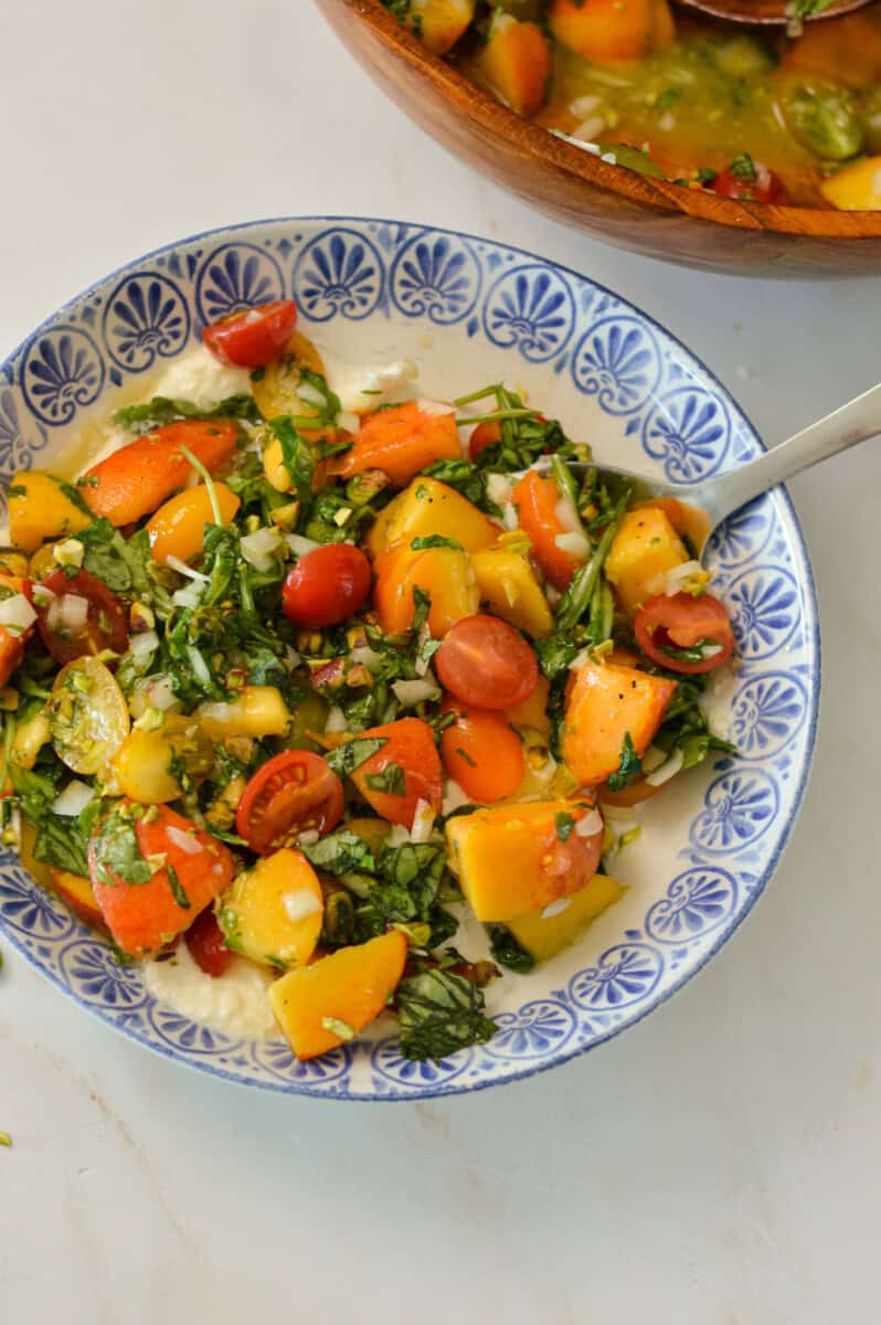Dressed peaches and tomatoes added to burrata and topped with pistachios.