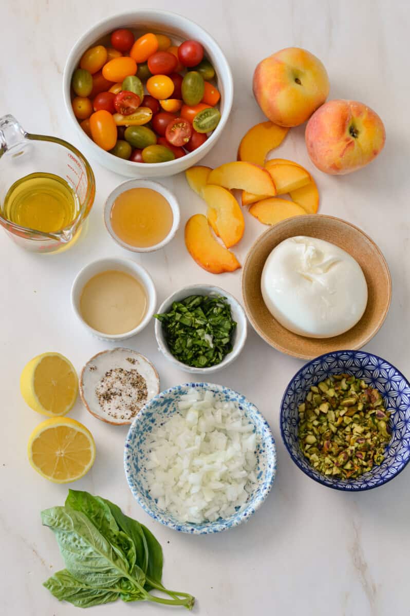 Ingredients for the easy summer salad including peaches, cherry tomatoes, burrata, shallots, fresh basil, apple cider vinegar, honey, salt and black pepper.