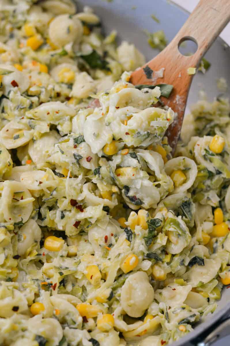 Close up of a spoon lifting up the zucchini pasta out of a pan.