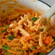 Scoop of high protein buffalo chicken pasta being lifted out of a pot.