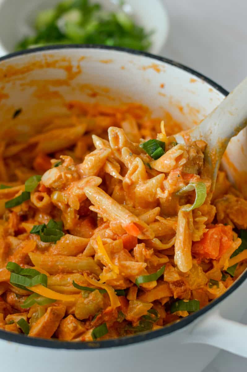 Scoop of high protein buffalo chicken pasta being lifted out of a pot.