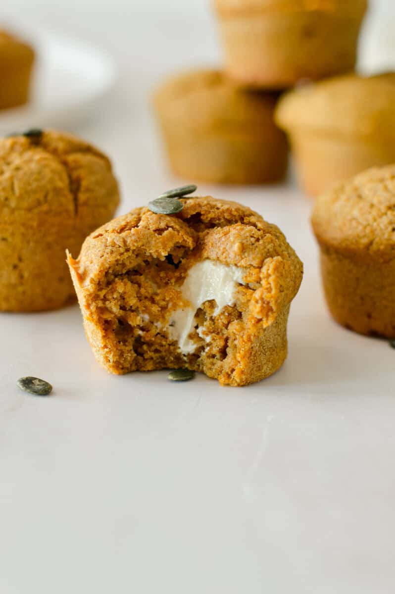 Pumpkin cream cheese stuffed muffin with a bite taken out of it.