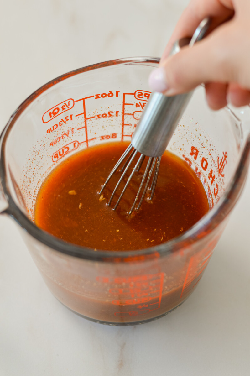 Gochujang sauce being whisked in a measuring cup.