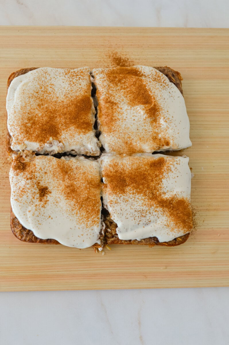Greek yogurt frosting added and cinnamon added to the top and sliced into four pieces.